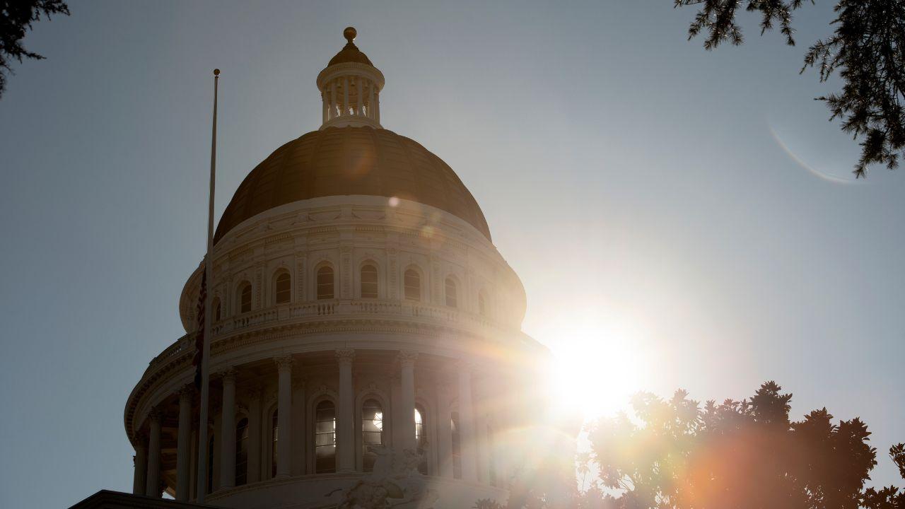 A lens flare is created by the sun shining out from behind the dome of the California State Capitol.